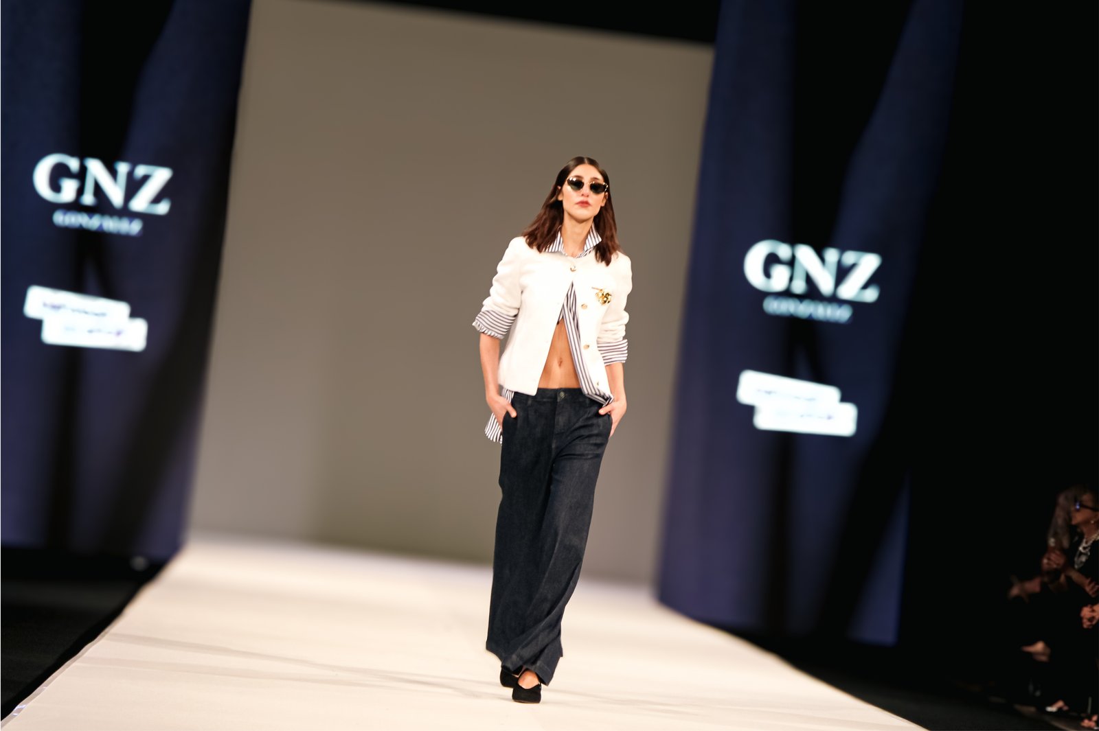 Modelo en pasarela con camisa blanca sobre fondo GNZ